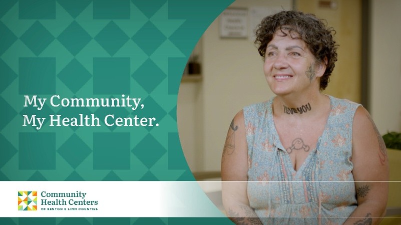 Woman with short curly brown hair, covered in tattoos and wearing a sleeveless floral top promotes the My Community, My Health Center campaign for the Community Health Centers of Benton & Linn Counties (CHC).