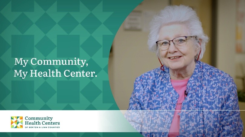 Woman with short white hair wearing glasses, a blue floral jacket, and a pink shirt promoting the My Community, My Health Center campaign for the Community Health Centers of Benton & Linn Counties (CHC).